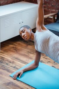 Die rutschfeste LIFORME Yogamatte. Dunkelhäutige Frau in Yoga Pose auf türkisfarbener Yogamatte